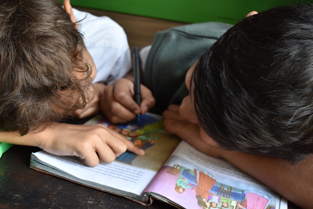 Two children learning together with a picture book